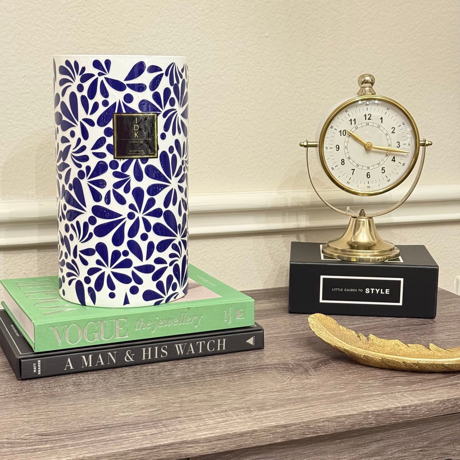 Decorative IDKandle candle displayed with books and a gold clock